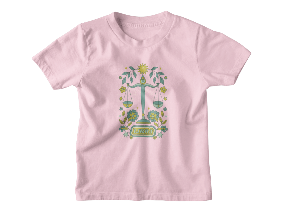 A light pink short-sleeve kids t-shirt with an astrology graphic of a green and gold scale of justice surrounded by tarot elements and the word &