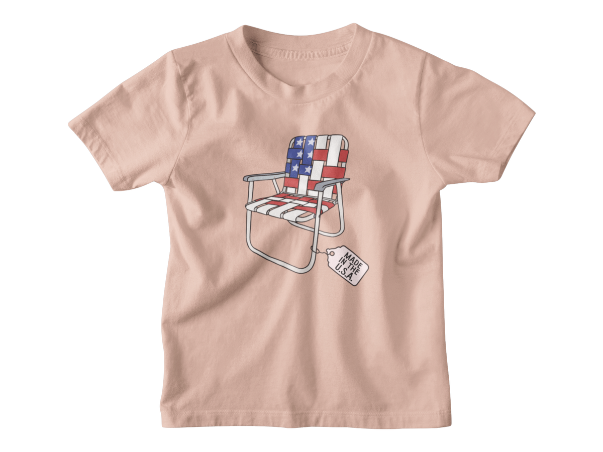 A peach short-sleeve kids t-shirt for 4th of July with a folding lawn chair featuring an American flag pattern, with a &