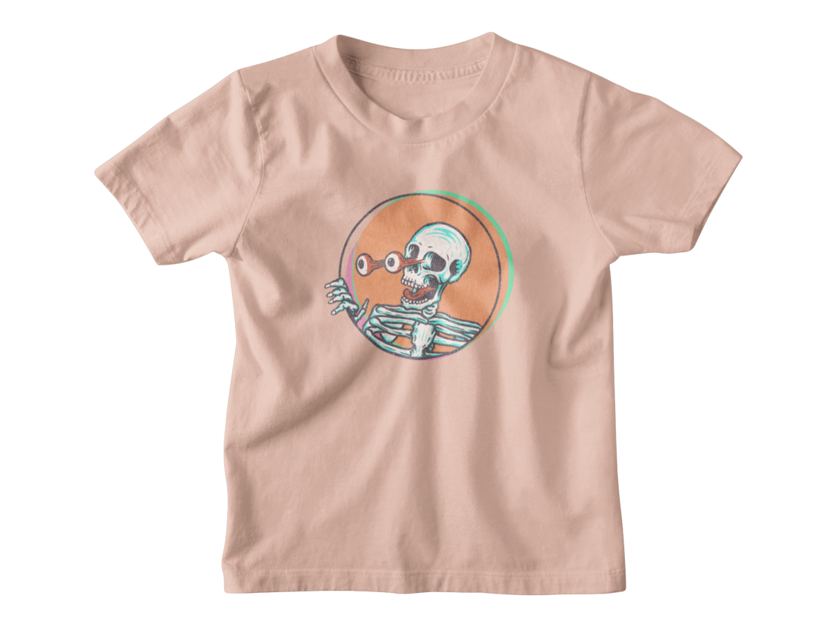 A light peach-pink short-sleeve t-shirt with a cartoon skeleton graphic inside a circular orange frame on the chest, displayed flat against a white background.