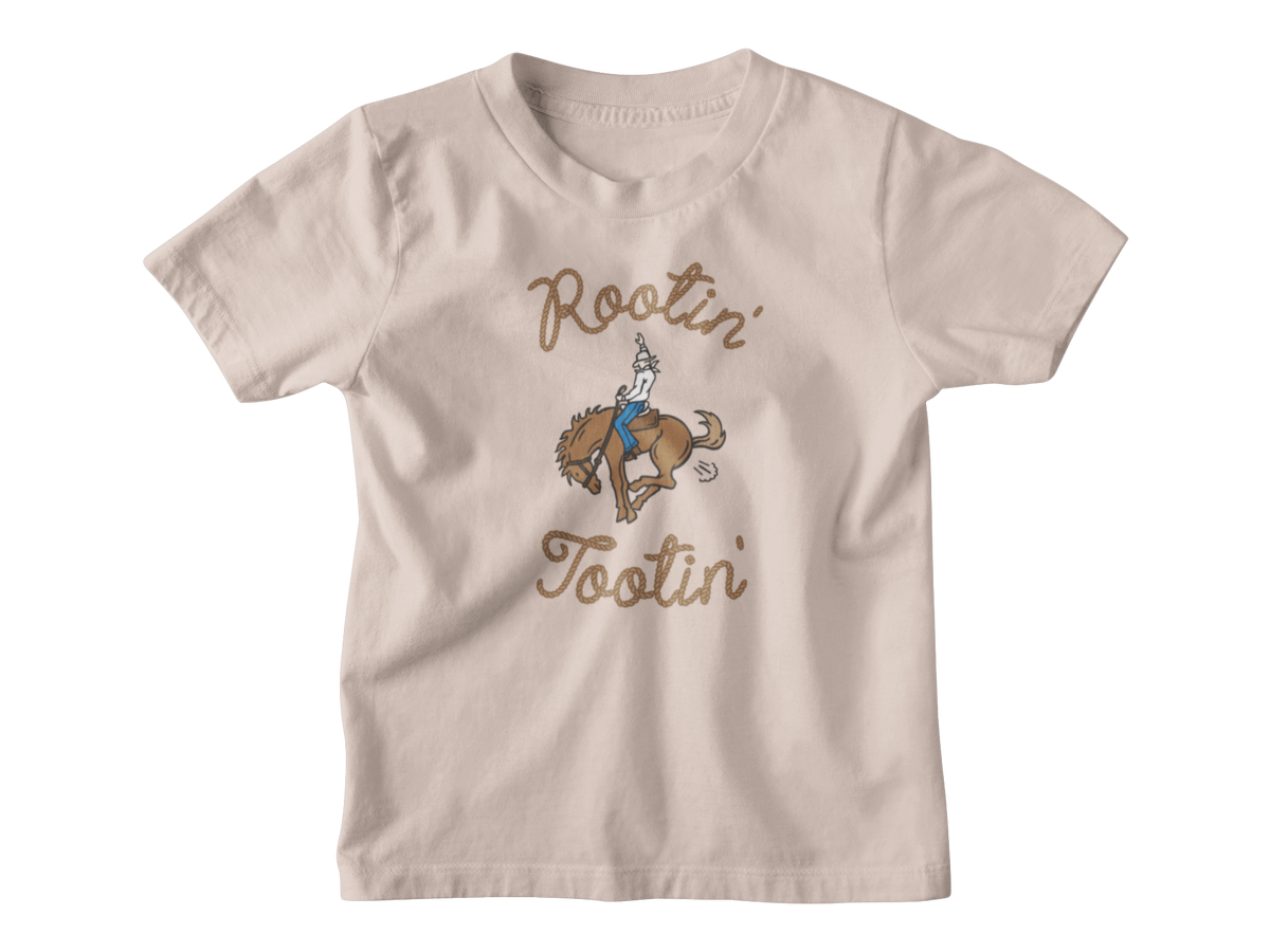 A light brown kids short-sleeve t-shirt with a graphic of a cowboy riding a bucking horse, surrounded by the words &