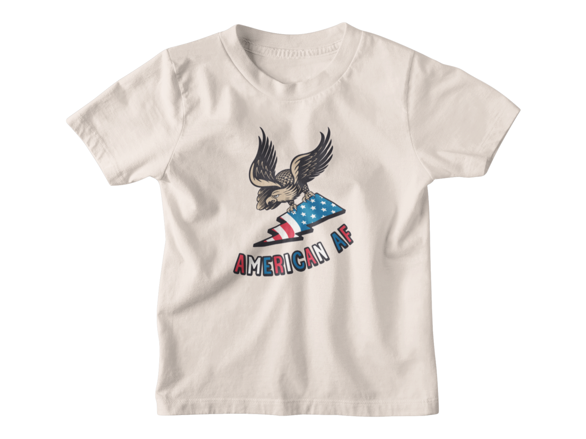 A cream colored short-sleeve t-shirt with a graphic of an eagle holding an American flag and the text &