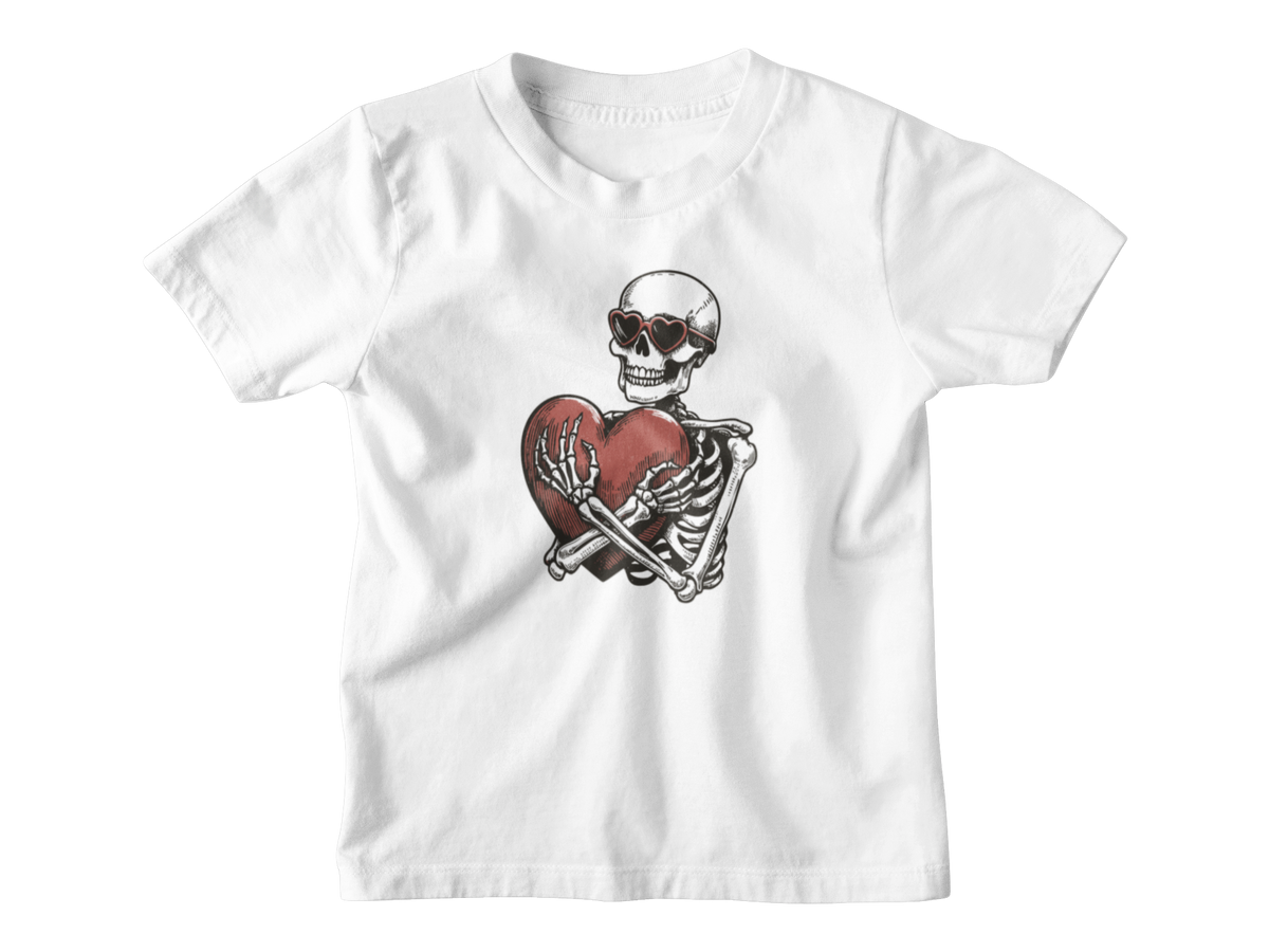 A white short-sleeve kids t-shirt with a graphic of a Halloween skeleton wearing sunglasses and holding a broken red heart, displayed on a clean white background.