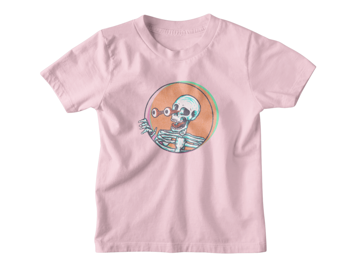 A light pink short-sleeve t-shirt with a cartoon skeleton graphic inside an orange circle on the chest, displayed flat against a white background.