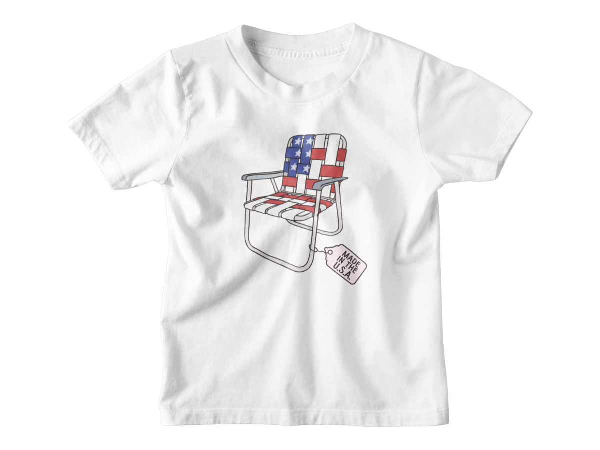 A white short-sleeve kids t-shirt for 4th of July with a folding lawn chair featuring an American flag pattern, with a &