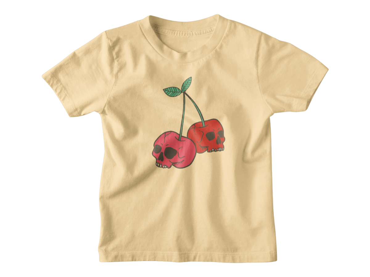 A pale yellow short-sleeve kids t-shirt featuring a graphic of two red cherries with skull faces and green stems, displayed on a clean white background.