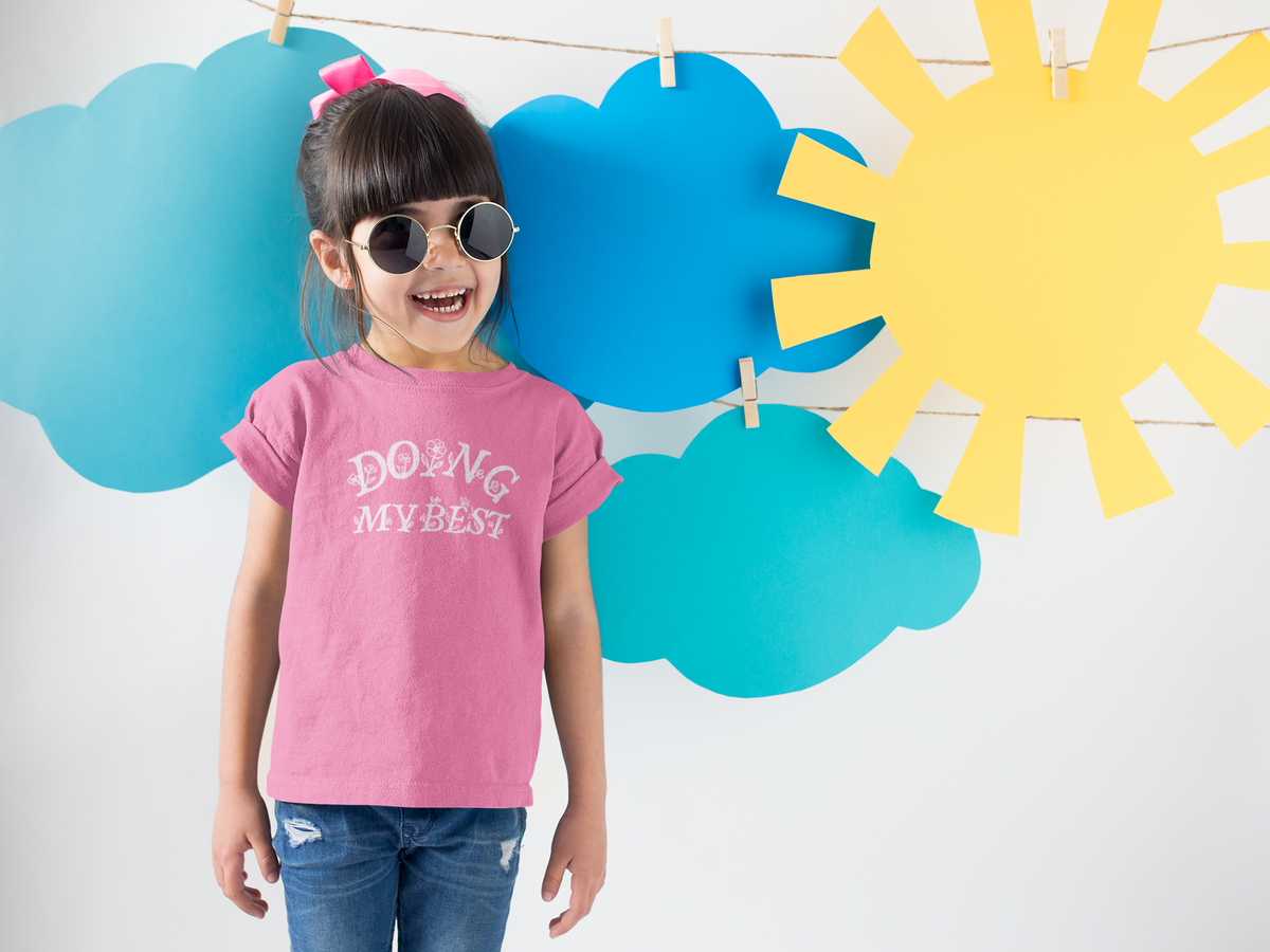 Smiling kid wearing a funny pink t-shirt with the phrase "Doing My Best".