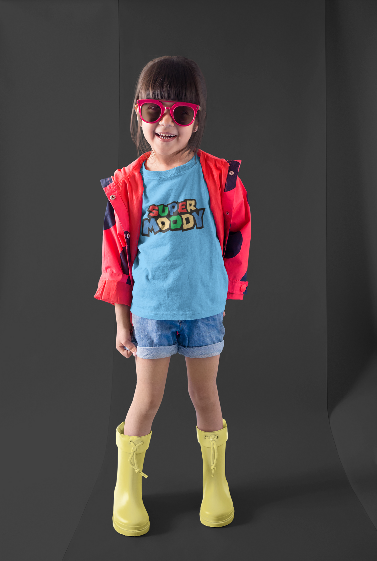 A kid wearing a blue tee that reads 'Super Moody' in Mario Brothers style with a red and navy jacket, denim shorts, yellow rain boots, and pink sunglasses.