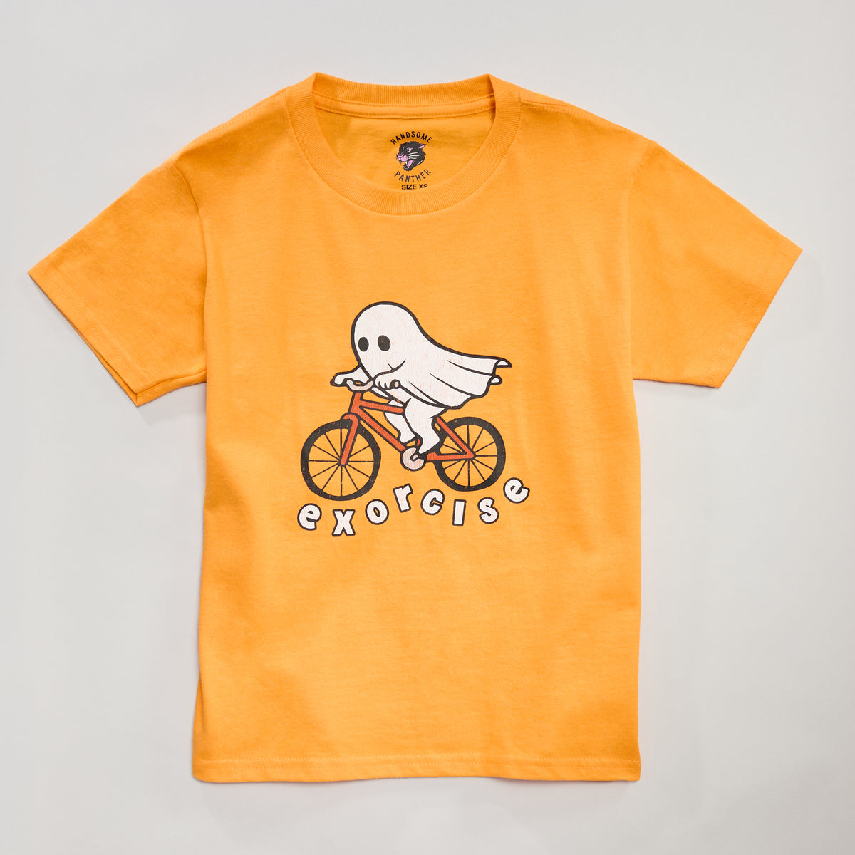 A bright orange kids or infants Halloween shirt featuring a ghost riding a bike with the phrase &
