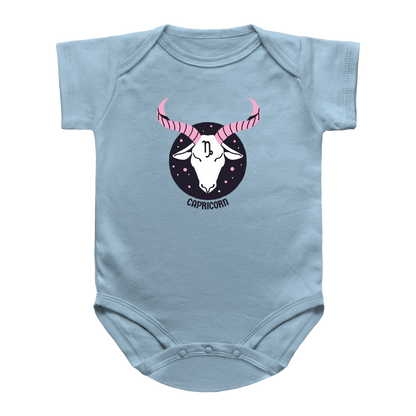 A light blue baby infant onesie featuring a printed graphic of a Capricorn zodiac sign. The graphic shows a white goat head with pink striped horns inside a black circle with stars, and the word &