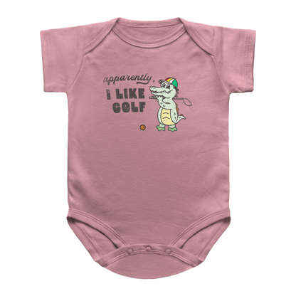 A dusty pink short-sleeve baby infant bodysuit featuring a cartoon alligator wearing a green and red striped golf hat, holding a golf club next to the text &
