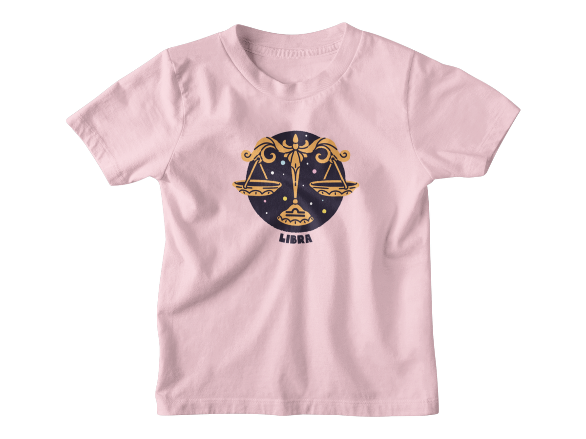 A pink short-sleeve t-shirt with a Libra zodiac graphic on the chest, featuring a gold scale of justice design over a dark blue circle with the word &